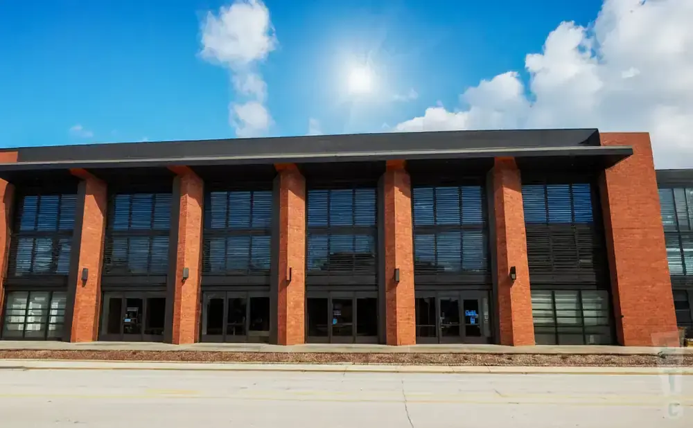 Modern brick building with large windows and glass doors under a blue sky.