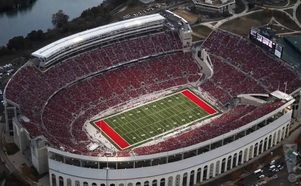 Aerial view of a packed football stadium with red seats and a green field with red end zones.
