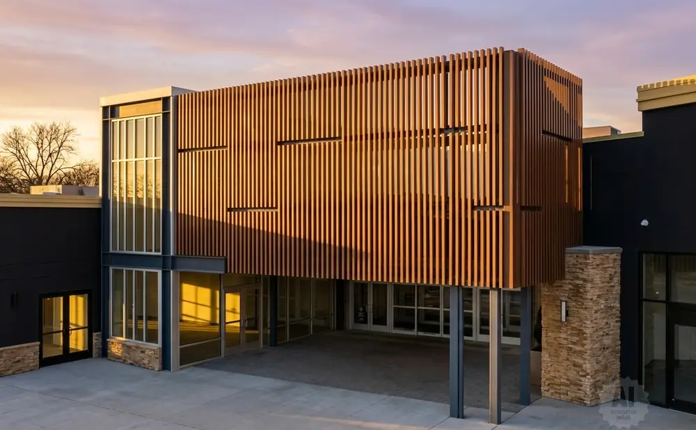 Modern building with wood-slatted facade and large windows at sunset.