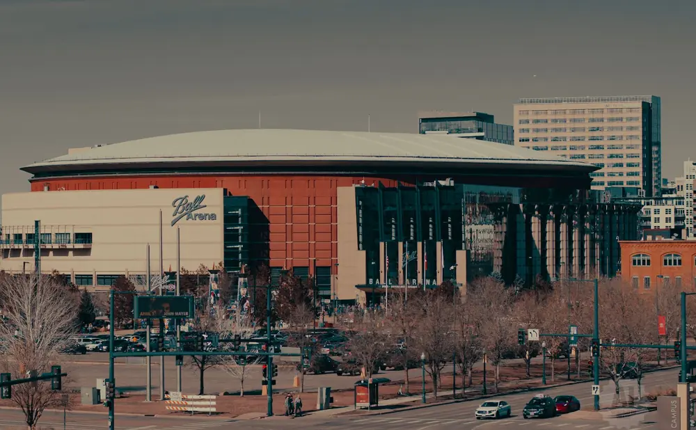Ball Arena in Denver, with surrounding buildings and trees.