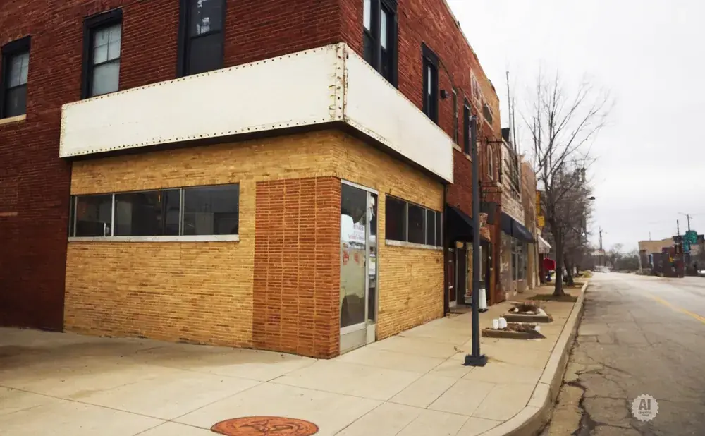 A brick building with a blank white awning and large windows on a cloudy day.