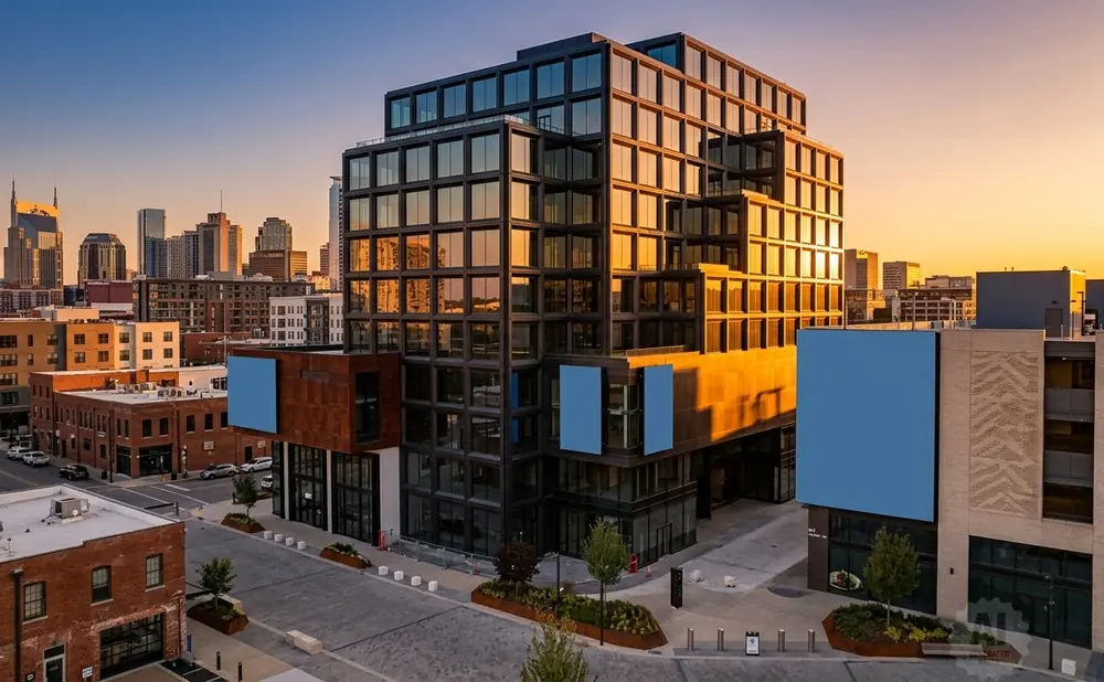 Modern glass buildings in a city skyline at sunset.