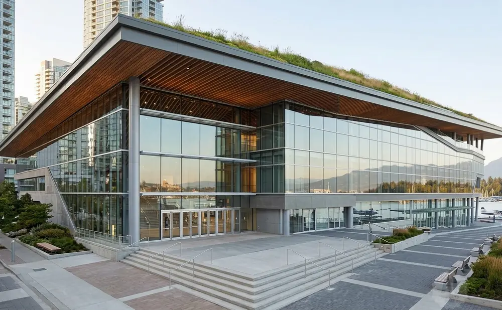 Modern convention center with a green roof, glass facade, and waterfront view.