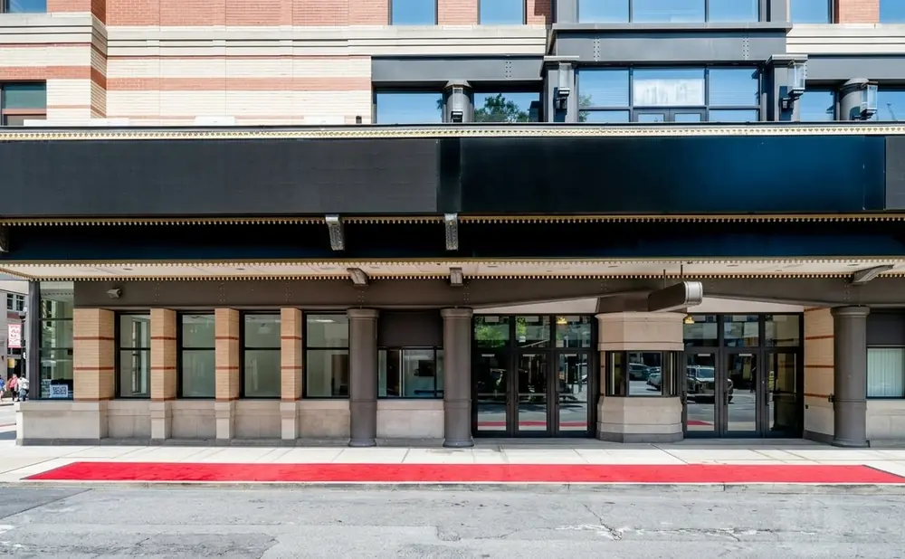 A red carpet leads to the entrance of a building with a black marquee and brick accents.