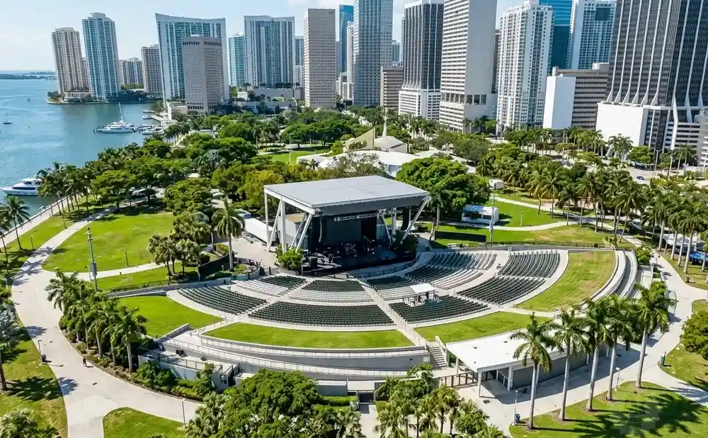Open-air amphitheater and stage with a city skyline and water in the background.