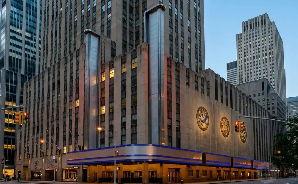 Art deco building in New York City with geometric patterns, ornate seals, and illuminated windows.