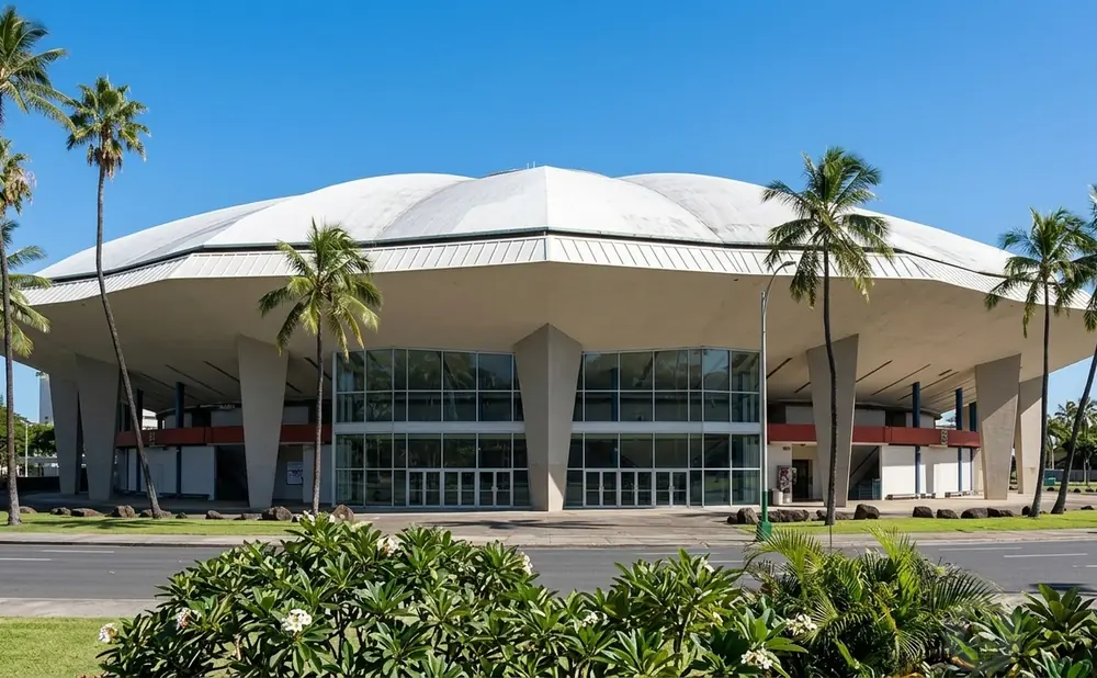 Large, futuristic dome-shaped building with glass facade and palm trees under a bright blue sky.