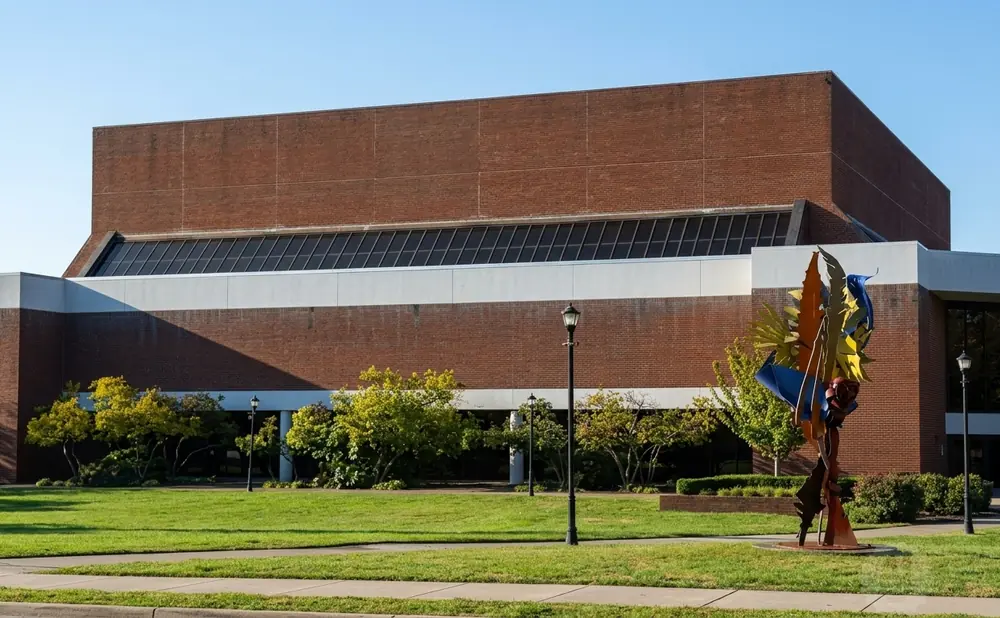 Sculpture in front of a large brick building with a band of windows.