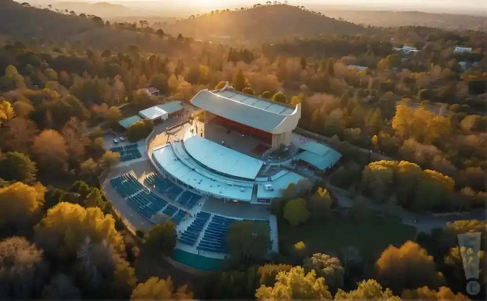 Aerial view of an outdoor amphitheater surrounded by trees with autumn foliage.