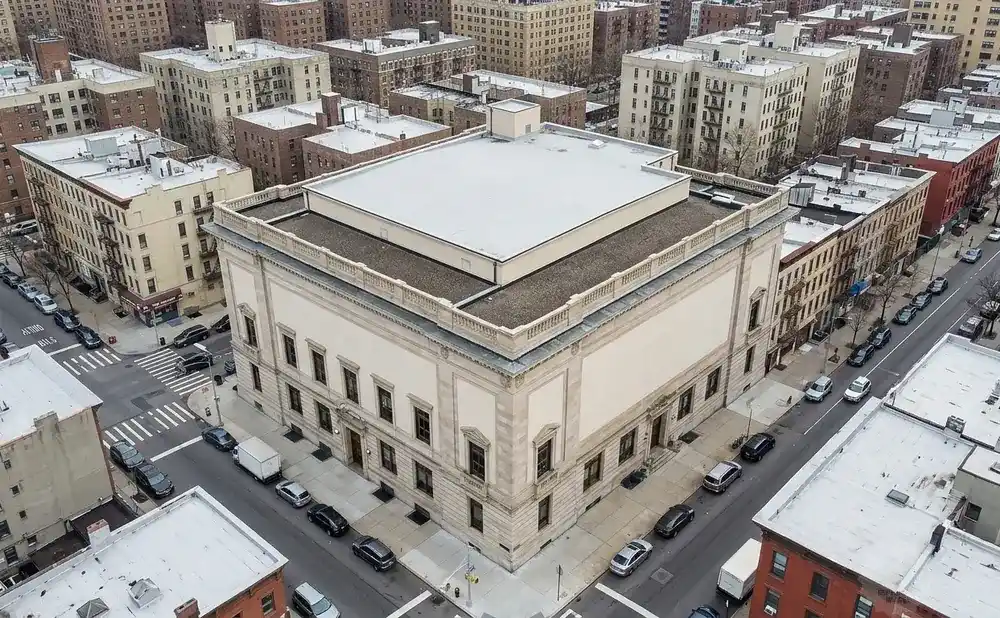 Aerial view of a city block with a large, light-colored building and surrounding apartment buildings.