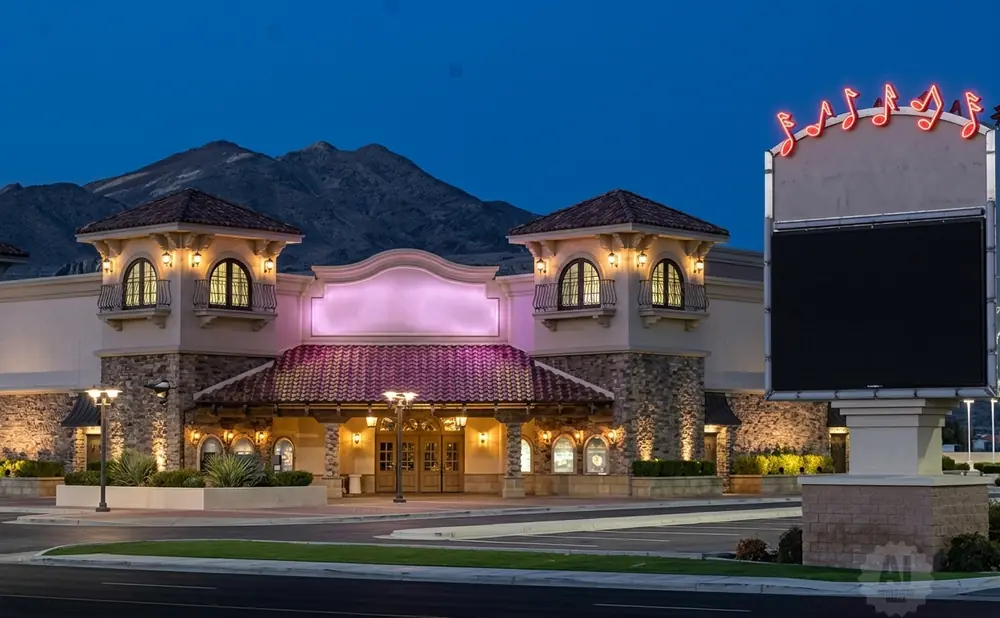 A lit-up casino with musical notes on a sign, under a twilight sky with mountains in the background.