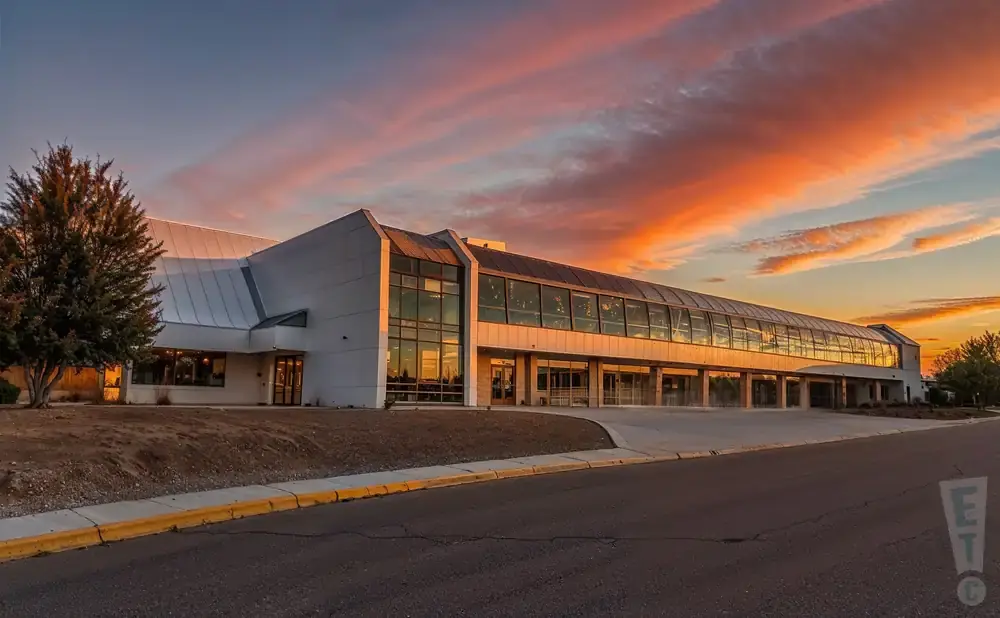 A modern building with a long glass-enclosed walkway during a vibrant sunset.