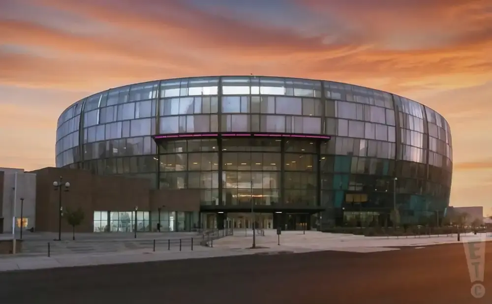 Modern circular building with glass facade at sunset.