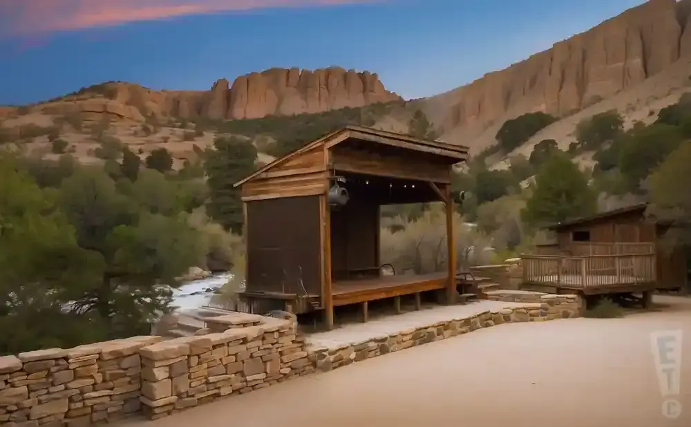 Outdoor wooden stage and deck in a canyon with a river and mountains.