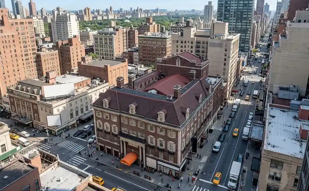 Aerial view of a bustling New York City street with tall buildings, traffic, and pedestrians.