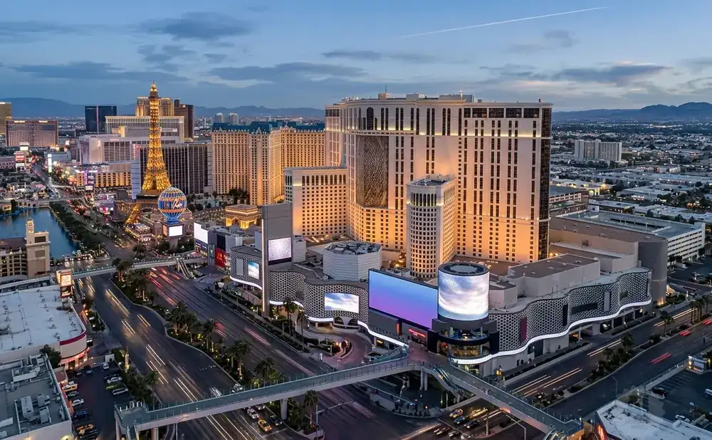 Las Vegas Strip at dusk, featuring the Eiffel Tower replica, hotels, casinos, and illuminated streets.