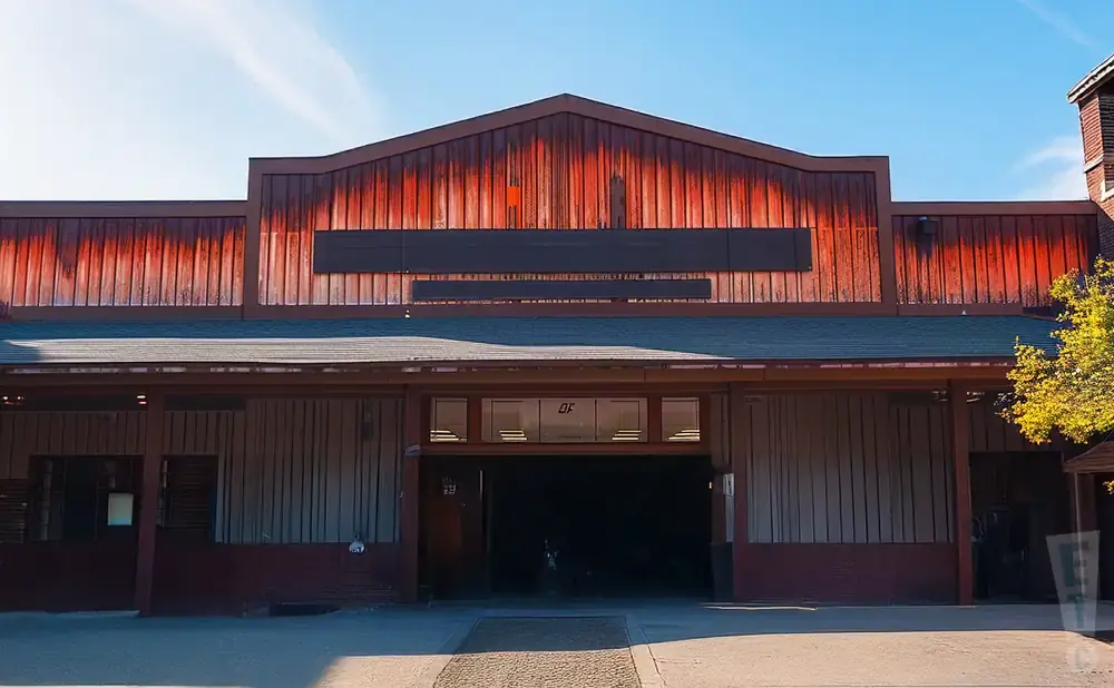 Exterior of a rustic building with a red corrugated metal roof and brown wooden walls.