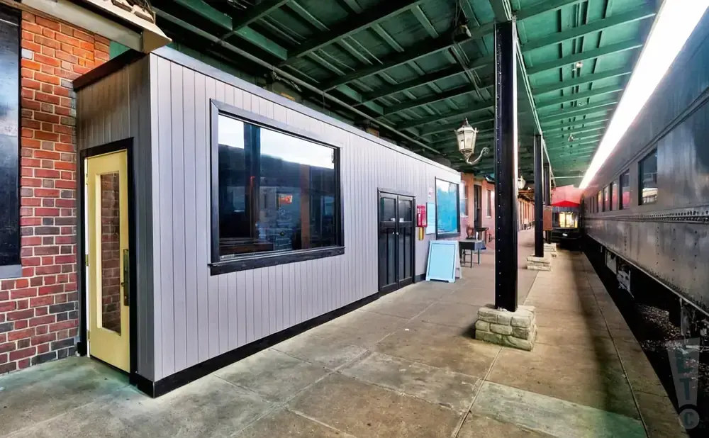 A train station with a modern building and a vintage train.