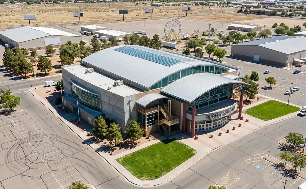 Aerial view of Tingley Coliseum, a large domed building with a curved facade, surrounded by parking lots and some greenery.