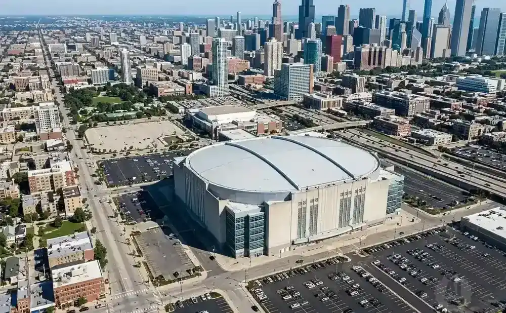 Aerial view of a large oval arena in a city with skyscrapers in the background.