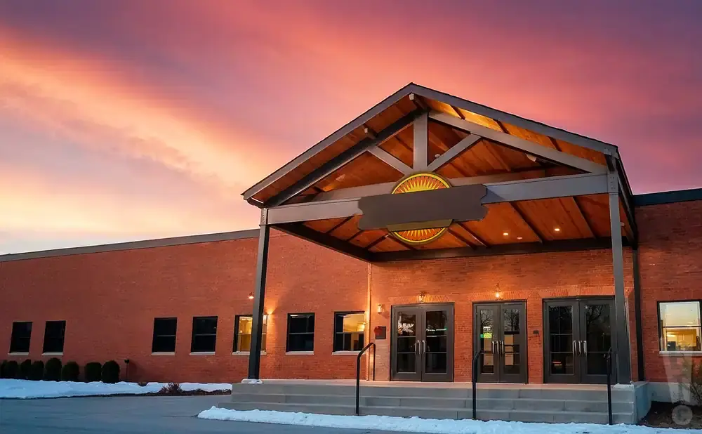 Exterior of a modern brick building with a covered entrance at sunset.