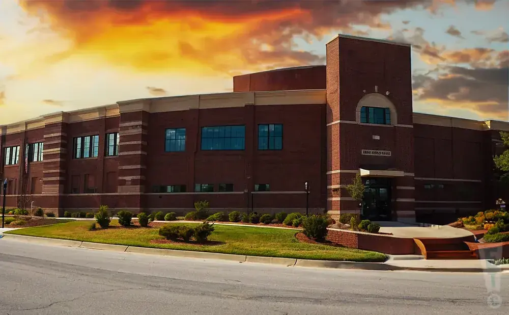 Brick building with a tower and banner under a dramatic sky.
