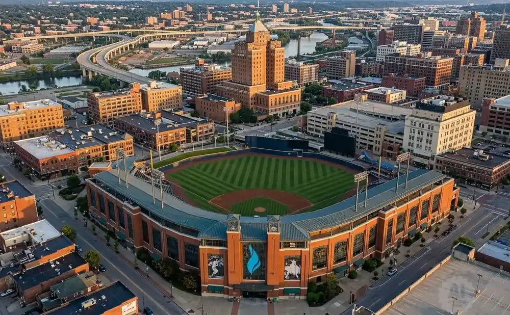 Aerial view of a baseball stadium in a city with buildings and a highway.