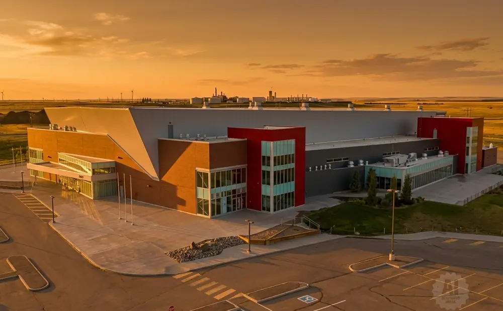 Exterior aerial view of a modern industrial building with brick and red accents at sunset.