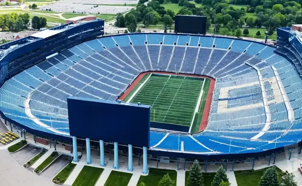 Aerial view of a large, mostly empty football stadium with blue seats and a green field.