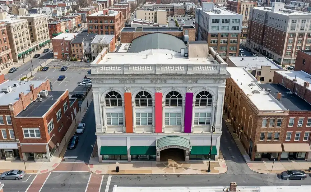 Aerial view of a city street with brick buildings and an ornate white building with colorful banners.