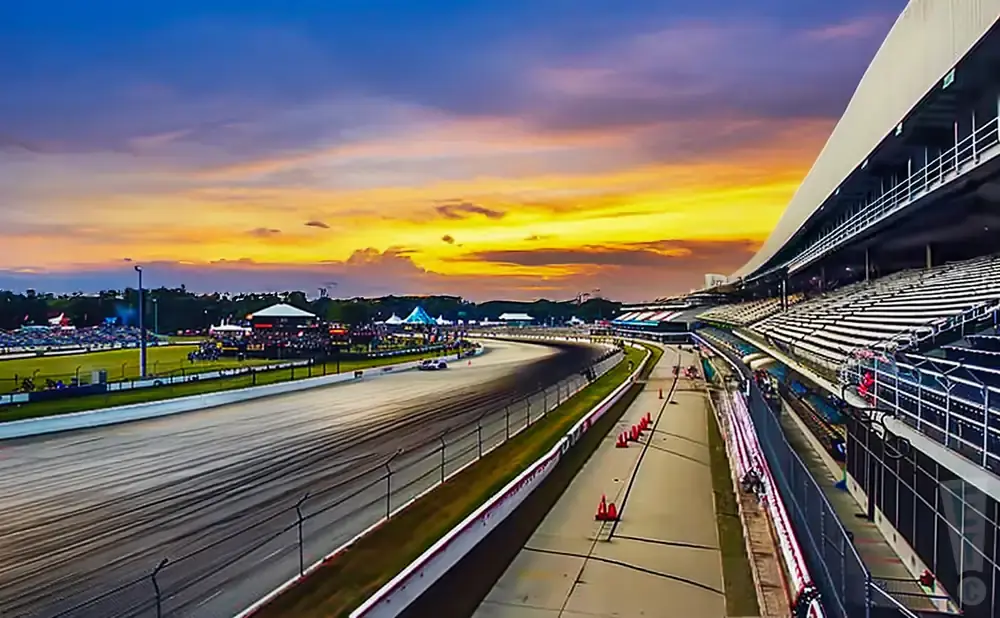 Race track with grandstands and a vibrant sunset sky.