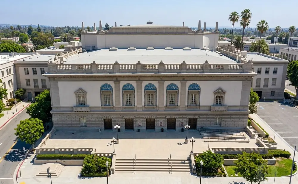 Grand building with columns, arched windows, and a balustrade, set against a clear blue sky.