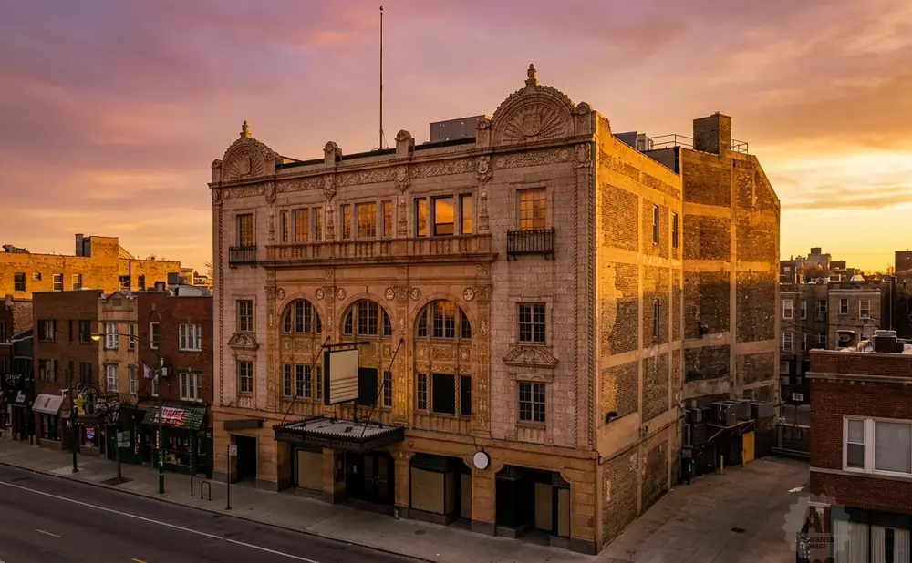 Ornate vintage building at sunset with glowing orange sky and purple clouds.
