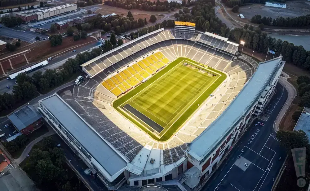Aerial view of a football stadium with yellow seats and a green field.