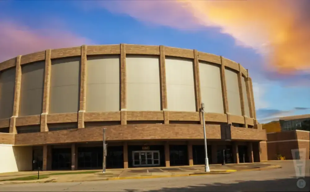 Large circular brick building with tall windows under a colorful sunset sky.