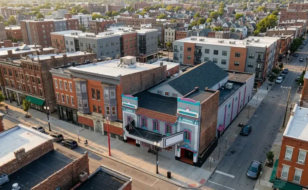 Aerial view of a city street lined with brick buildings and modern apartments, with a theater in the foreground.