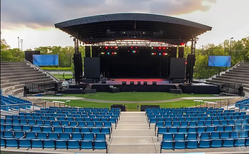 Outdoor amphitheater with a stage, seating, and screens.
