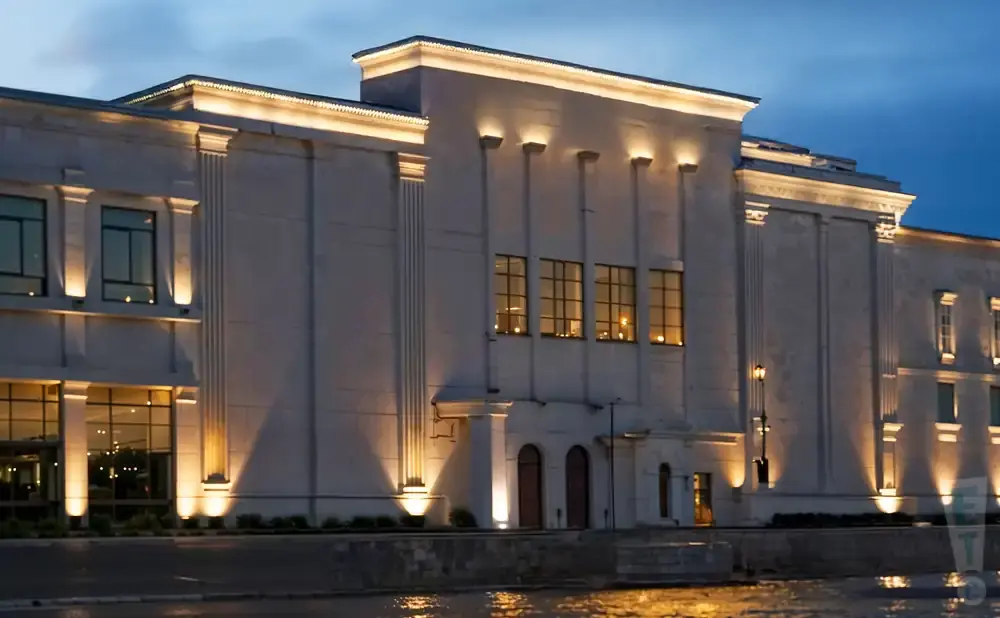 A lit, modern building with large windows, lit at dusk.