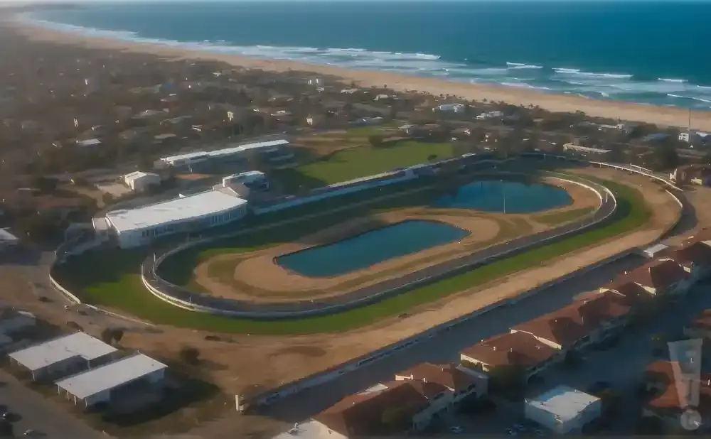 Aerial view of a racetrack by the ocean, with buildings and pools.