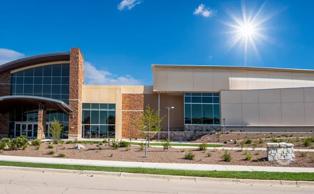 Modern building with large windows and stone accents under a bright sun.