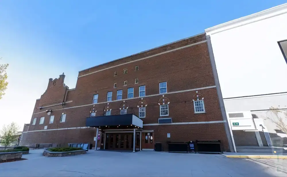A large brick building with a white section on the right, under a blue sky.