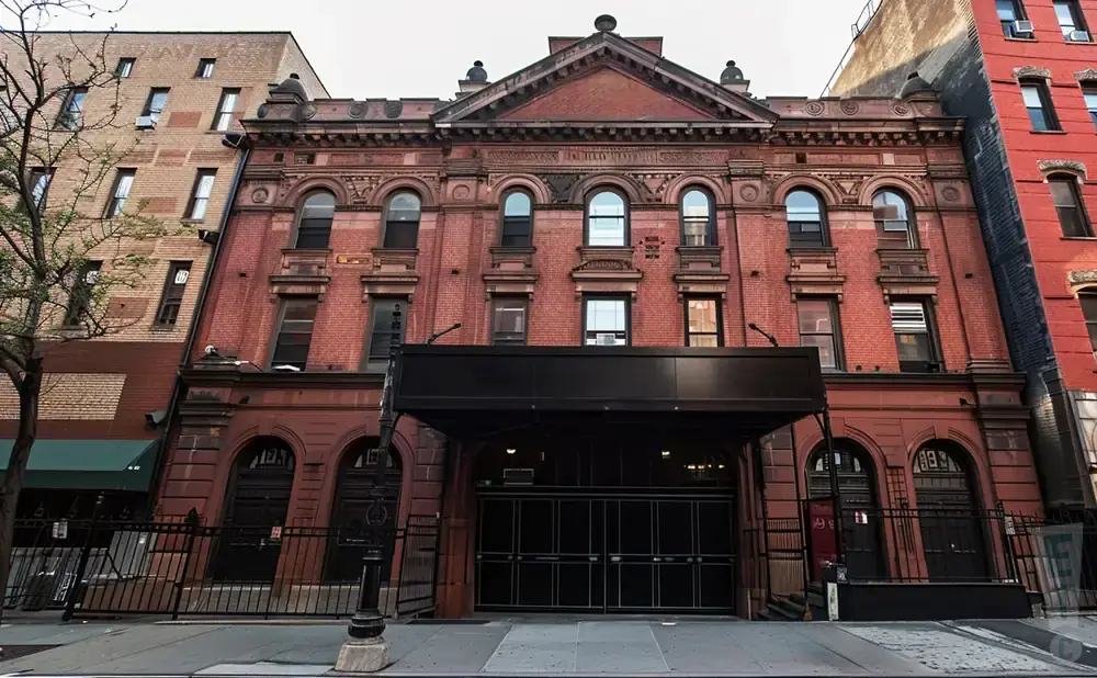 Exterior of a red brick building with arched windows and an entrance canopy.