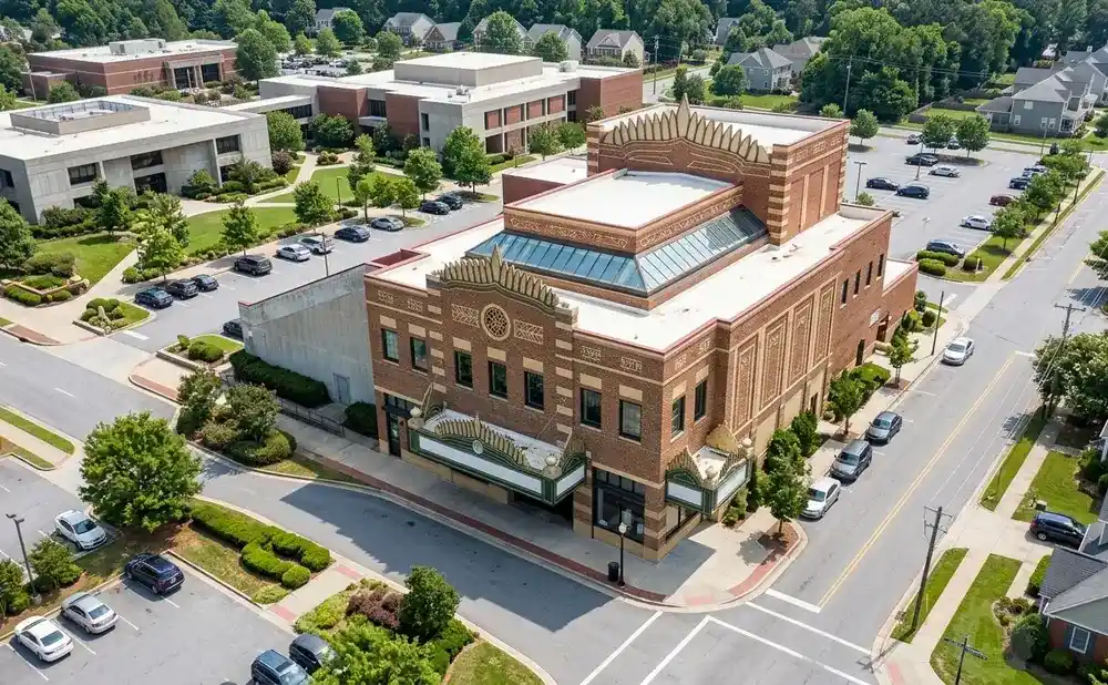 Aerial view of a brick theater building with a marquee, surrounded by parking lots and residential homes.