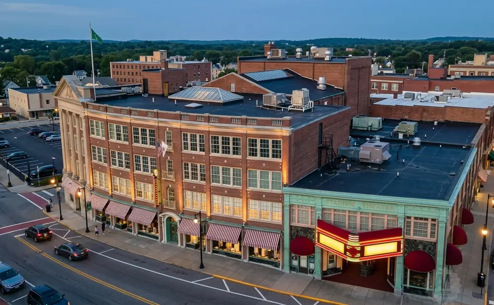 Aerial view of a town square with a brick building featuring a theater marquee and striped awnings.