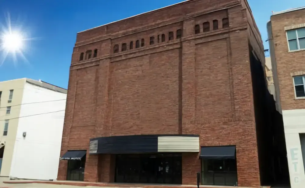 Exterior of a red brick building with dark awnings over storefronts.