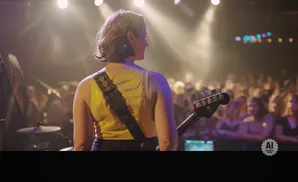 A woman plays guitar on stage in front of a crowd, lit by spotlights.