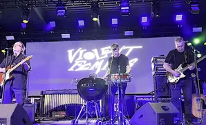 Violent Femmes performing live with band members playing guitar, bass, and drums.
