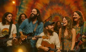 A band plays music with guitars and smiles on a stage.