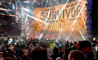 WWE Survivor Series War Games stage with bright lights and a crowd.