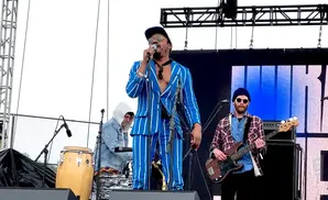 Band performing on stage with a lead singer in a blue pinstripe suit.